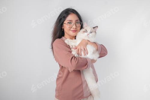Preview: Lovely Asian woman wearing eyeglasses holding her ragdoll cat and smiling to the camera.