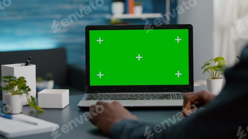 Preview: Close up of african american man using green screen laptop in bright living room