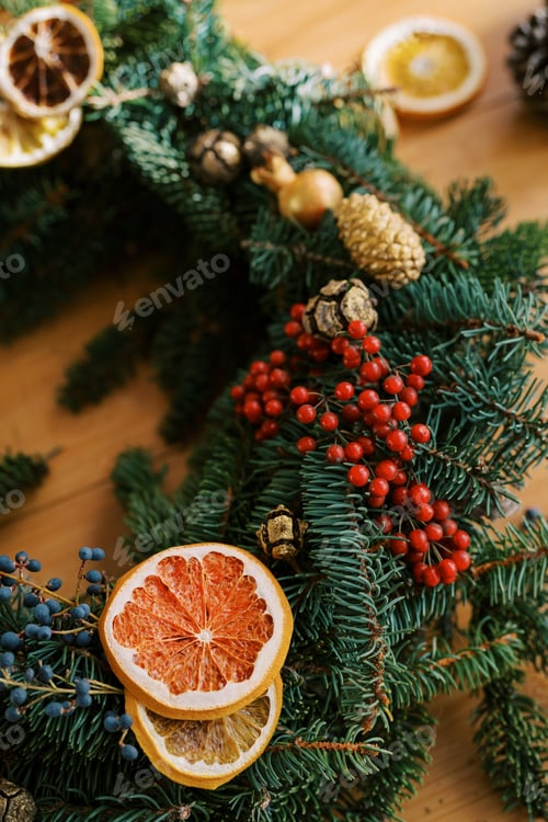 Preview: Christmas wreath is decorated with red and blue berries, pine cones and dried orange slices. Cropped