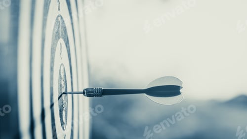 Preview: Close up red dart arrow hitting target center dartboard on sunset background. Business targeting and