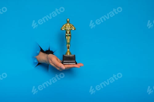 Preview: Hollywood Golden Oscar Academy award statue in hand isolated on white background. Success and
