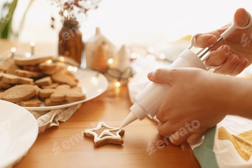 Preview: Hands decorating baked christmas star cookie with sugar frosting. Family christmas time