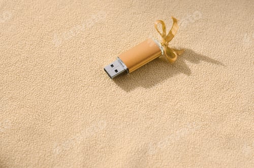 Preview: Orange usb flash memory card with a blue bow lies on a blanket of soft and furry light orange fleece