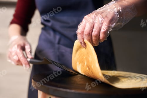 Preview: Chef hands turn over crepe with spatula helping on portable cooktop. Baking process.