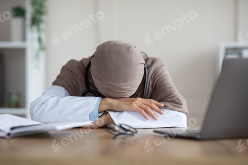 Preview: Overworked female doctor having nap at workdesk