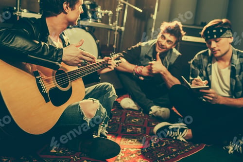 Preview: selective focus of musician holding acoustic guitar near cheerful friends