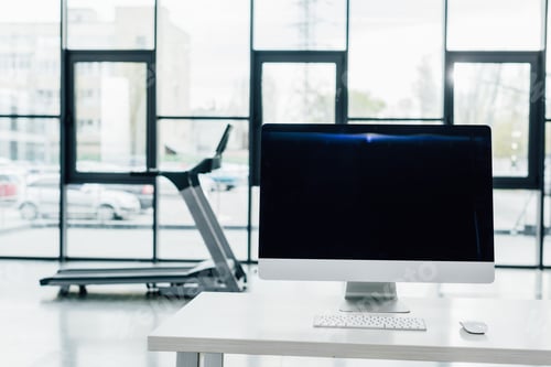 Preview: selective focus of computer with blank screen on desk near treadmill at sports center