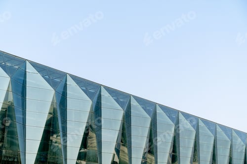 Preview: Modern geometric glass architecture under blue sky.
