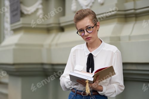 Preview: student with a book in his hands outdoors reading Lifestyle