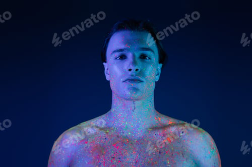 Preview: portrait of charismatic man with naked shoulders posing in radiant and colorful neon body paint and