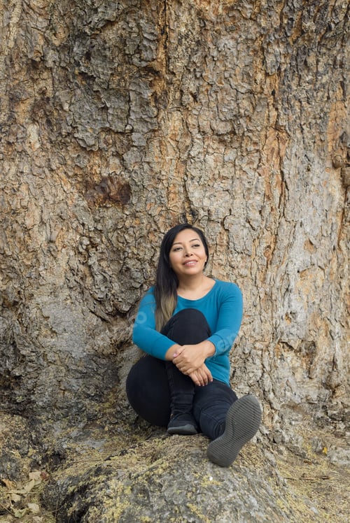Preview: Portrait of a woman leaning on a tree trunk.