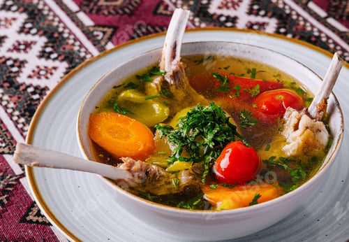 Preview: Traditional lamb soup with vegetables on patterned tablecloth