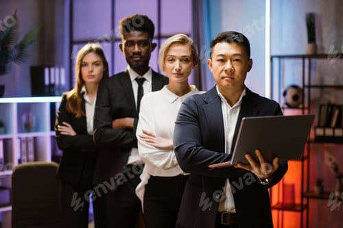 Preview: Diverse company workers standing in a row in creative office, posing on camera with arms folded.