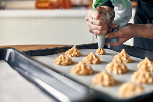 Preview: beautiful caucasian lady cook is making eclairs with help of pastry casing at home