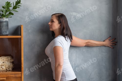 Preview: Young caucasian woman stretching hand at home.