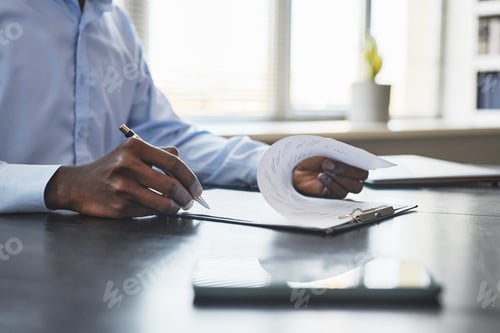 Preview: Black businessman signing document at desk in office