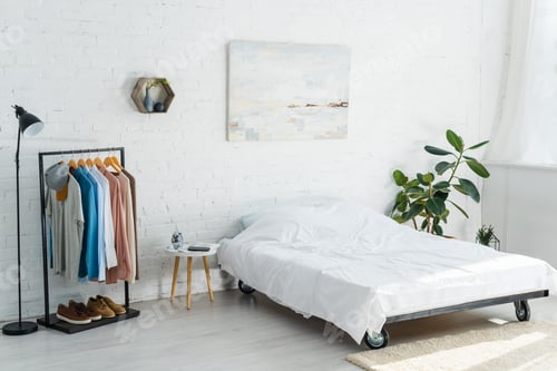 Preview: bed, clothes rack with shirts, plant, floor lamp and coffee table in bedroom