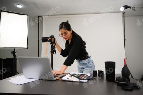 Preview: Portrait of female photographer with professional camera working in modern studio