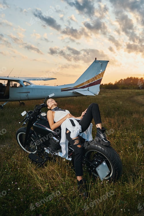 Preview: Young relaxed brunette leaning on her motorbike