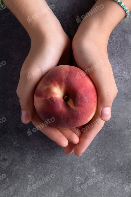 Preview: Woman's hands holding a fresh peach on dark gray background