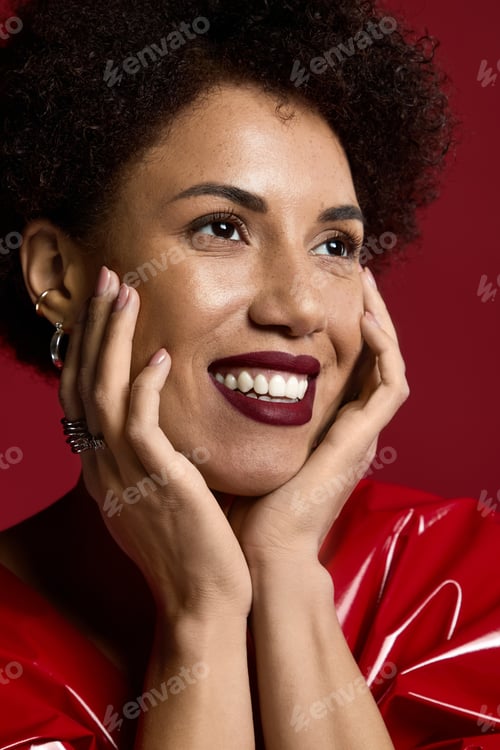 Preview: Captivating young woman smiles radiantly in elegant red attire against a bold backdrop