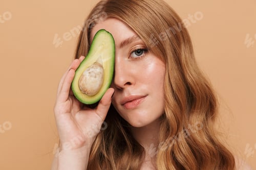 Preview: Portrait of young gorgeous shirtless woman holding half of avocado fruit