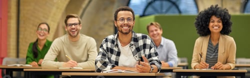 Preview: Young cheerful mixed race male office worker sitting with collegues in coworking space and