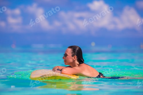 Preview: Beautiful fitness surfer woman surfing during summer vacation
