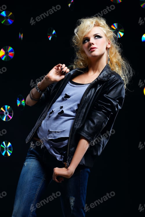 Preview: Potrait Of Beautiful Blonde Girl Glam Rocker In Leather Jacket. Multiple Shiny Cds On Dark