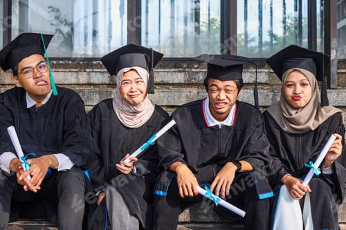 Preview: Group of multiethnic university student in graduation clothes showing funny face after celebration