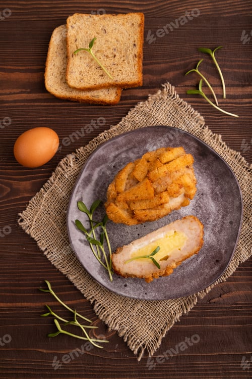 Preview: Chicken Schnitzel on gray plate with microgreen on brown wooden and linen textile. top view