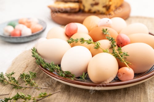 Preview: Homemade easter colored eggs on plate and raisins cake on a gray concrete background and linen texti