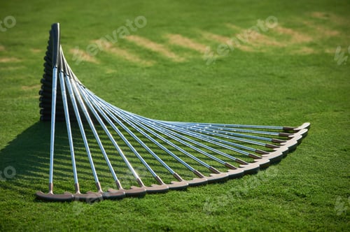 Preview: Row of aligned golf putters forming an arc on a green grass field, unique composition, professional