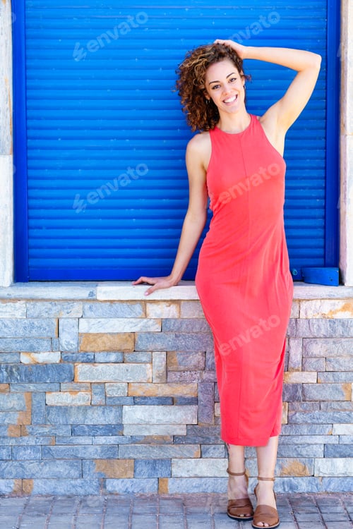 Preview: Stylish woman in red dress standing near blue shutters