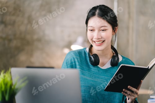 Preview: Smart and positive Asian female freelancer or student studying online webinars or courses at home. V