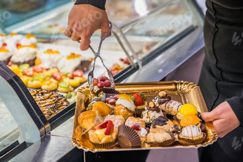 Preview: Close up of hands of the pastry man grabbing a tray of pastry to serve to a customer in the bakery