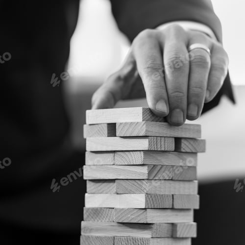 Preview: Black and white square format image of businessman placing domino