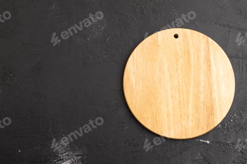 Preview: Empty round wooden cutting board on black concrete. Top view, copy space
