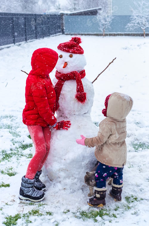 Preview: Children make a snowman in winter. Selective focus.