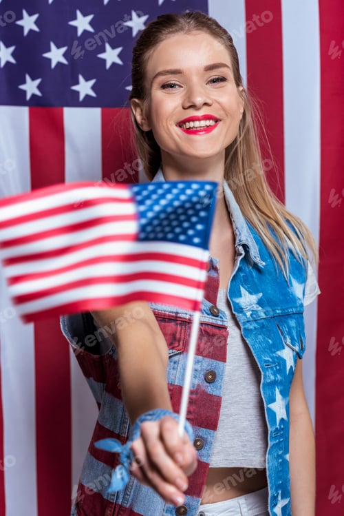 Preview: Attractive young woman holding american flag in hand and smiling at camera, woman celebrating