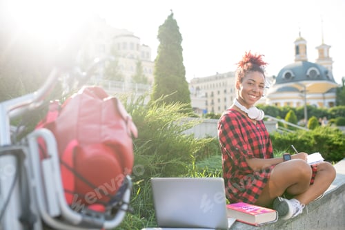 Preview: Student studying outside using laptop and books