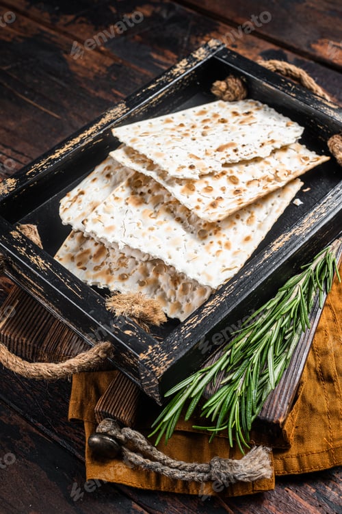 Preview: Passover matzos of celebration with matzo unleavened bread in a wooden tray with herbs.