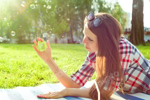 Preview: Woman Lying on Blanket Holding Alarm Clock