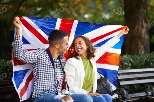 Preview: Happy young couple of tourists with a UK flag