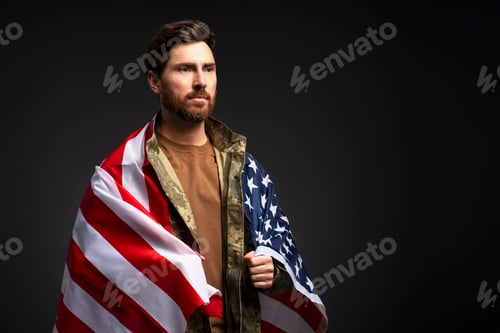 Preview: Soldier wearing military camouflage uniform holding American flag isolated on black background