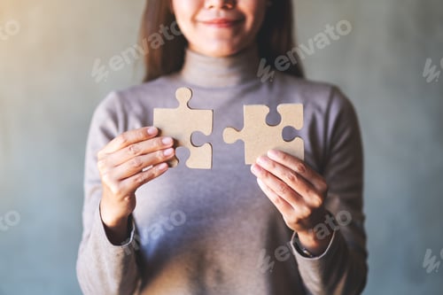 Preview: Closeup image of a woman holding and putting a piece of wooden jigsaw puzzle together