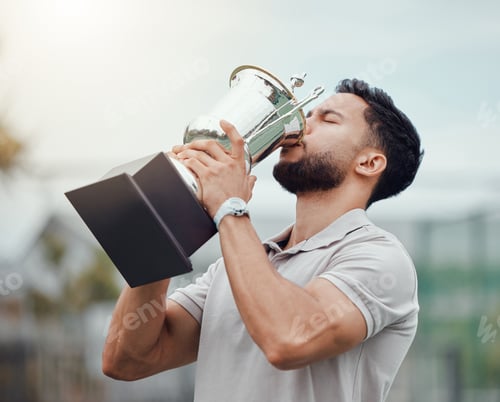 Preview: Mixed race tennis player drinking from trophy while celebrating success after winning court game. H