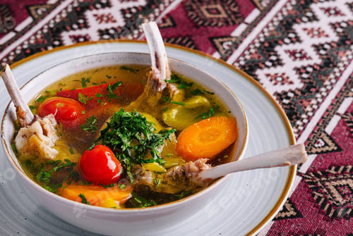 Preview: Traditional lamb soup with vegetables on patterned tablecloth