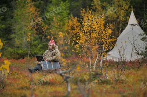 Preview: solar charging hiker working on tablet while camping