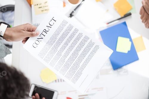 Preview: Overhead view of businessman holding contract above table with papers